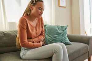 Woman experiencing IBS while lying on the sofa at home